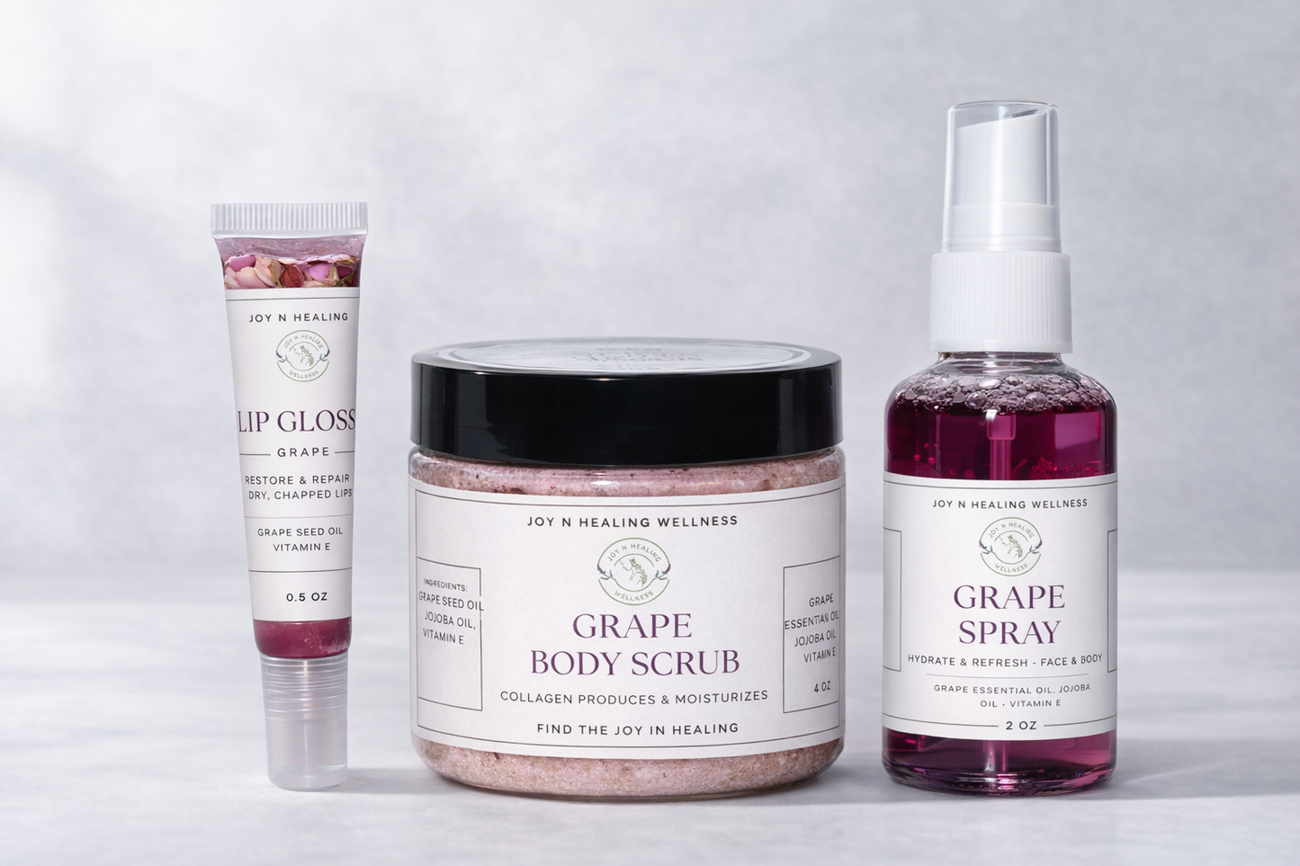 Collection of grape-themed skincare products including lip gloss, body scrub, and spray on a light gray background.