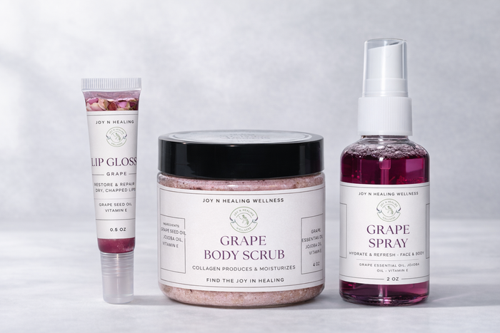 Collection of grape-themed skincare products including lip gloss, body scrub, and spray on a light gray background.