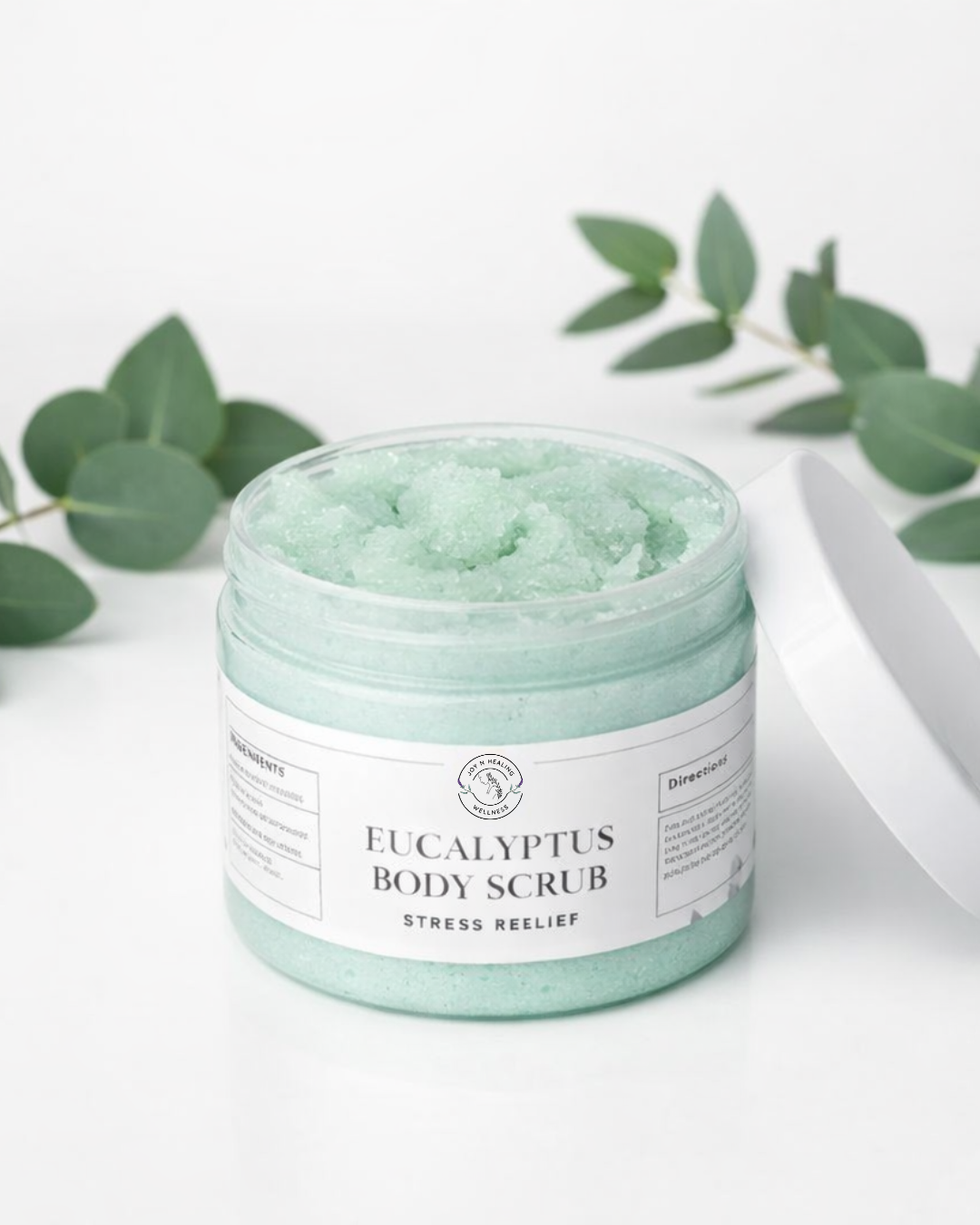 Jar of Eucalyptus Body Scrub with eucalyptus leaves on a white background